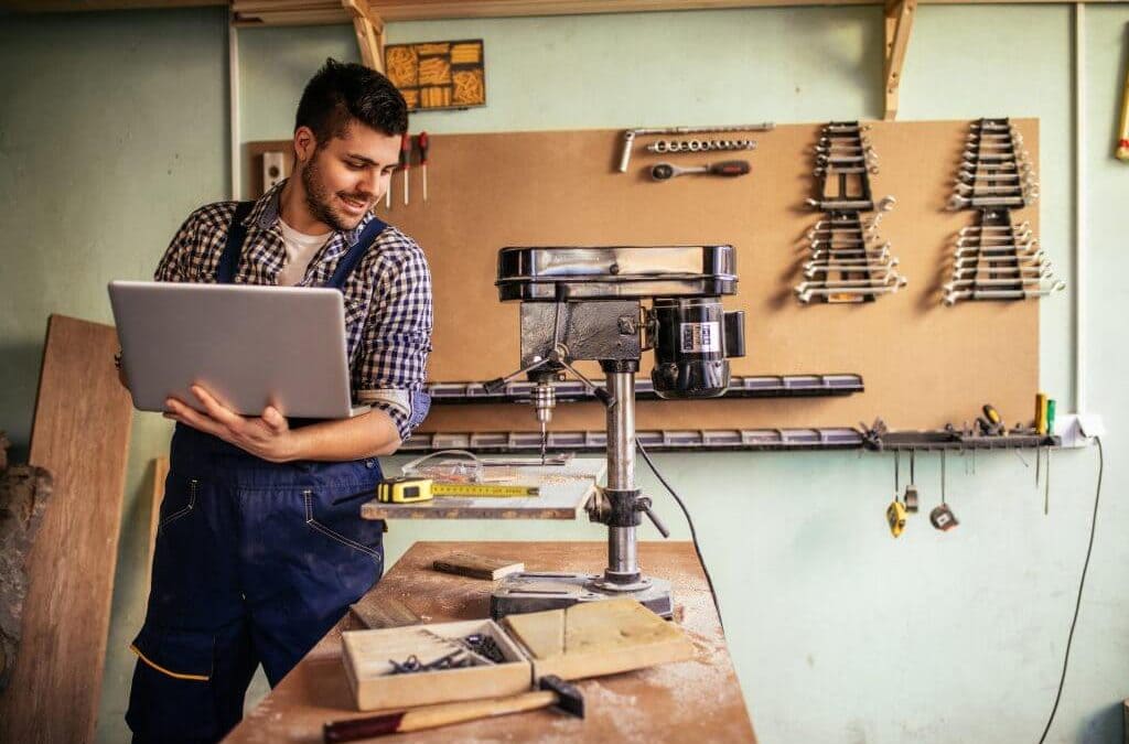 artisan du bâtiment dans son atelier, il tient un ordinateur entre ses mains