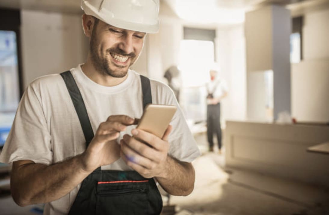 artisan du bâtiment qui regarde tolteck sur son téléphone depuis un chantier