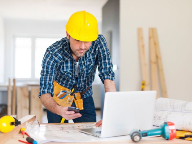 Artisan du bâtiment travaillant sur son ordinateur