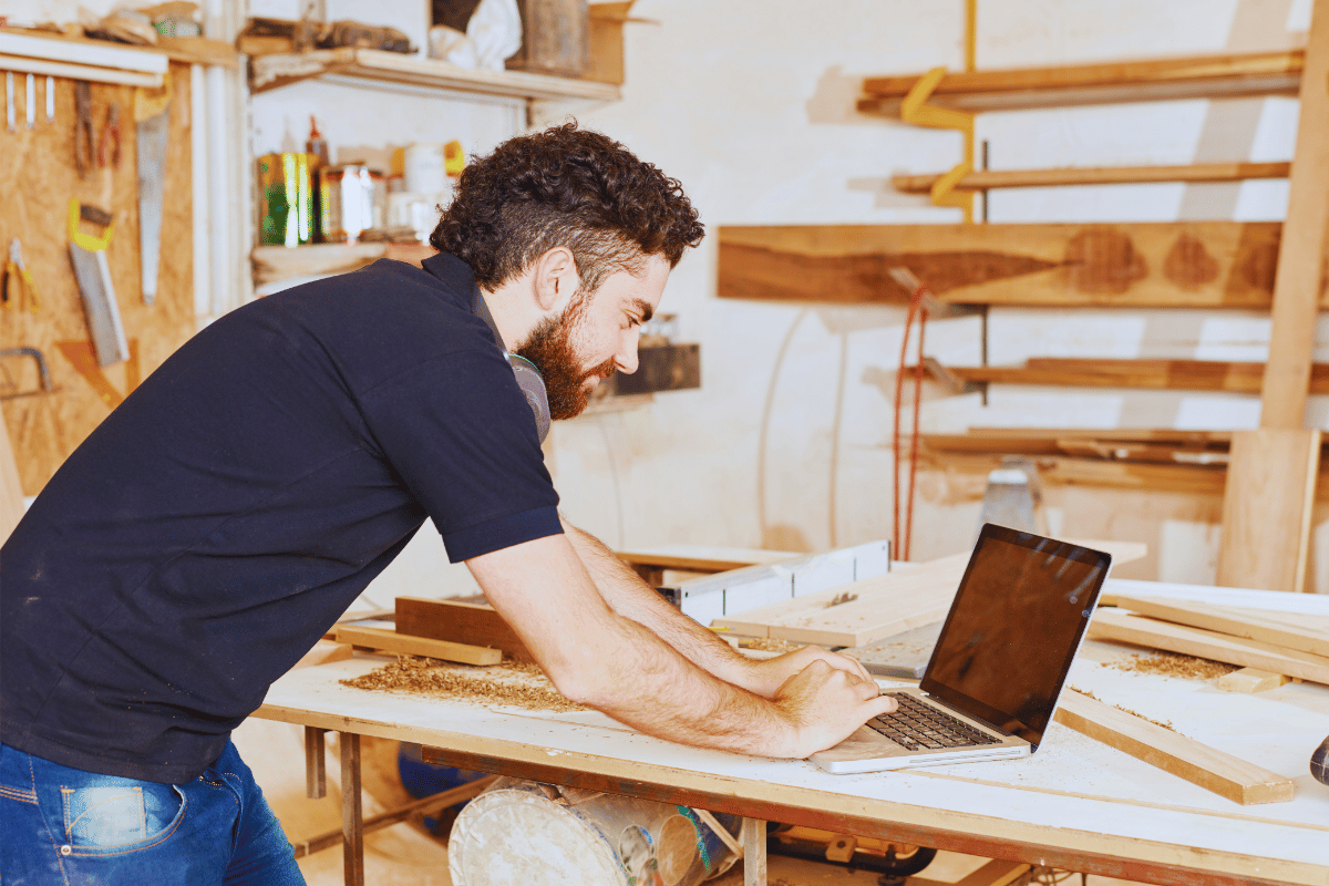 Artisan-menuisier-devant-ordinateur Un artisan menuisier entrain de faire sa facture electronique sur un ordinateur avec Tolteck